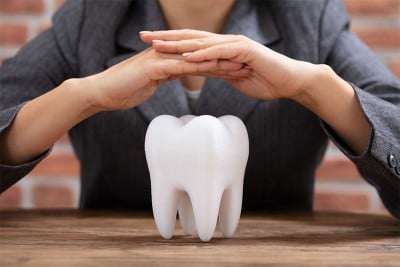 woman's hands hovering over an enlarged single tooth