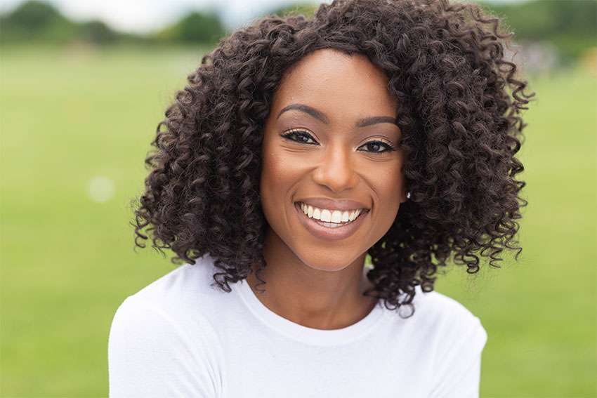 curly haired woman shows off her bright, white smile