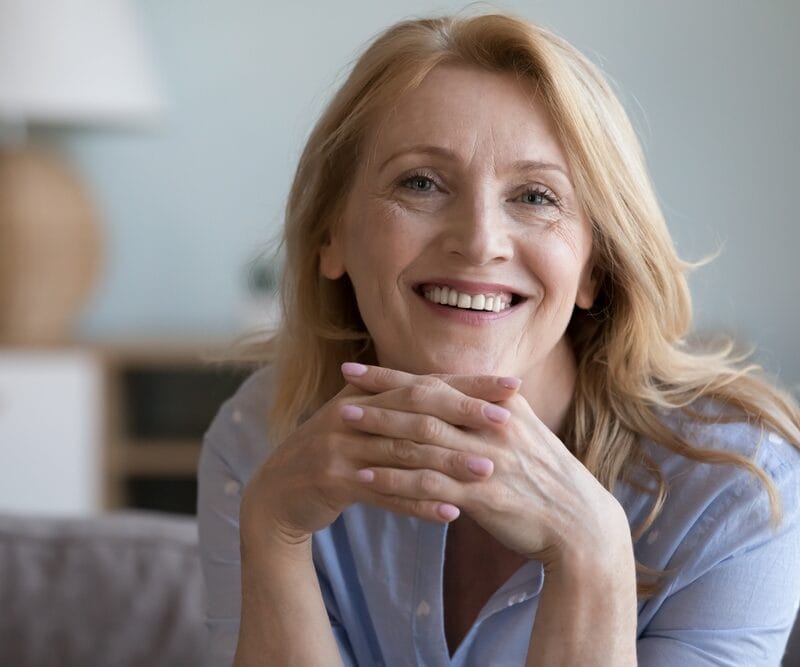 Confident older woman with a glowing smile and relaxed posture, showcasing the transformative results and renewed self-esteem from a smile makeover