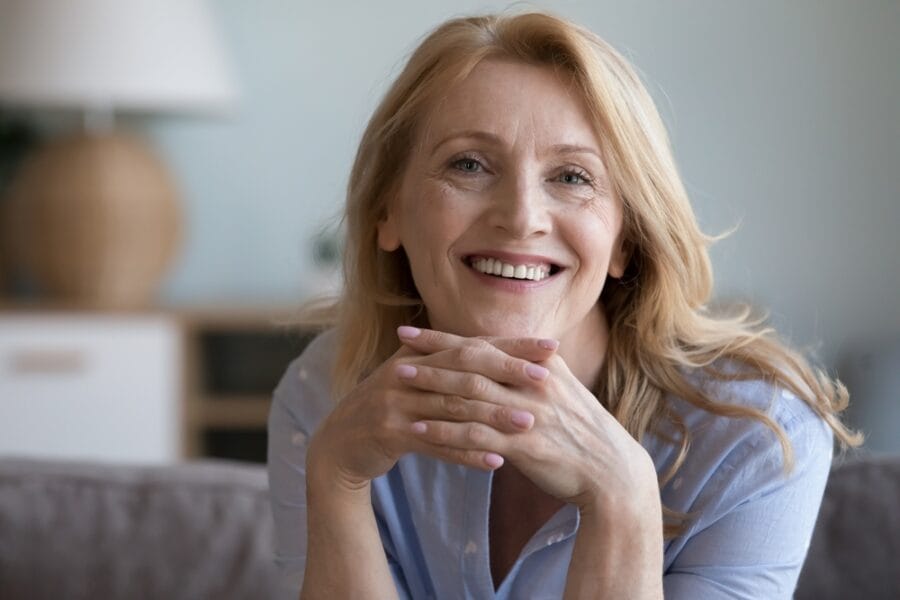 Confident older woman with a glowing smile and relaxed posture, showcasing the transformative results and renewed self-esteem from a smile makeover
