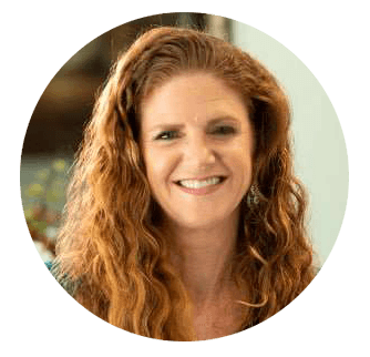 Dr. Stephanie Kinsey, with long curly red hair, smiling warmly in a professional setting – Palencia Dental