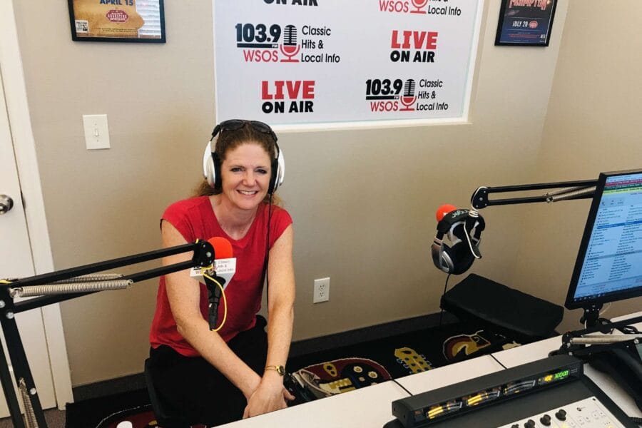 Smiling woman with headphones in a radio station studio, sitting between microphones during a live broadcast discussing TMJ disorders and sleep apnea