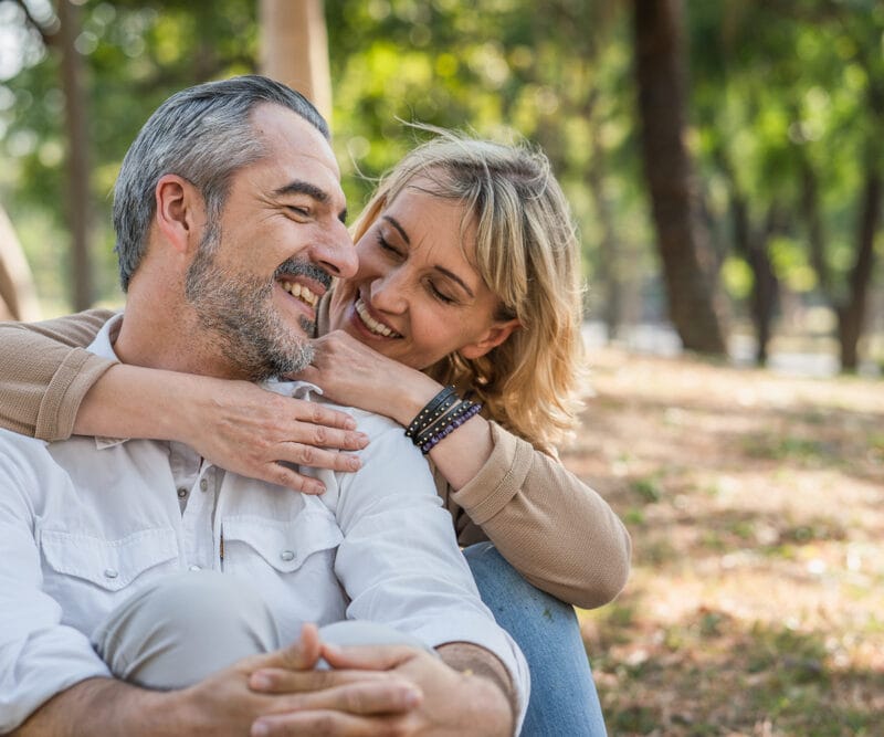 Happy middle-aged couple embracing in a park, symbolizing relief, trust, and restored comfort after receiving timely care from an emergency dentist