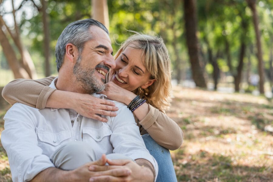 Happy middle-aged couple embracing in a park, symbolizing relief, trust, and restored comfort after receiving timely care from an emergency dentist