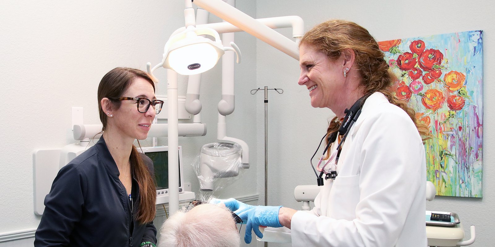 Dr. Stephanie Kinsey in a white coat at the chair with her dental assistant and a patient at Palencia Dental